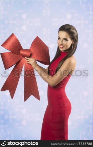 pretty brunette woman with happy expression posing in christmas portrait with sexy red dress and big red bow