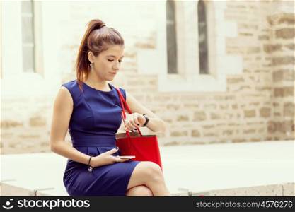 Pretty business woman looking at her watch. Pretty business woman looking at watch sitting outside