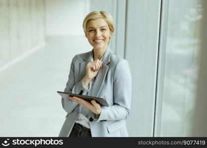 Pretty business woman standing with digital tablet in the office corridor