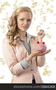 pretty business woman with pink jacket and curly elegant hair-style taking piggybank in the hand and smiling.