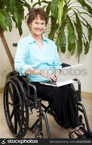 Pretty businesswoman in a wheelchair, using a netbook to wirelessly surf the internet.