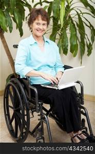 Pretty businesswoman in a wheelchair, using a netbook to wirelessly surf the internet.