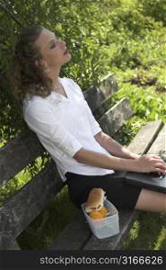 pretty businesswoman relaxing in the shade, with her laptop on her lap