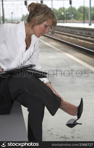 Pretty businesswoman rubbing her feet which hurt after having worn high heels all day