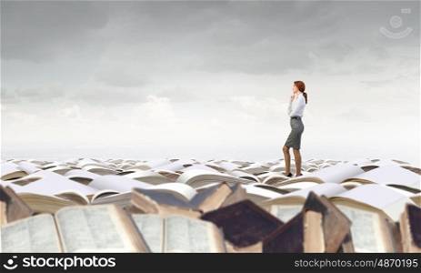 Pretty businesswoman standing on pile of books. Knowledge advantage