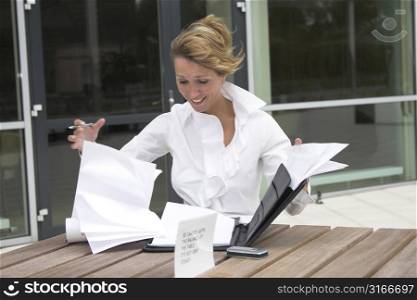 Pretty businesswoman trying to control her papers in the wind