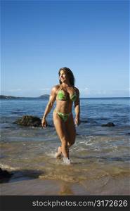 Pretty Caucasian mid adult woman bodybuilder in bikini walking through water on Maui beach.