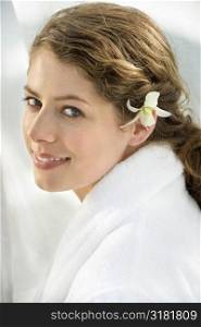 Pretty Caucasian mid-adult woman wearing white terry robe with white orchid flower in hair.