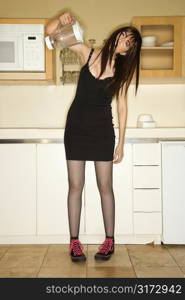 Pretty Caucasian young woman standing in kitchen holding empty blender.