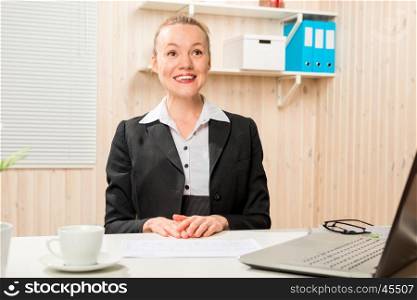 Pretty cheerful woman in a suit behind a computer