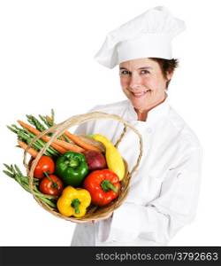 Pretty chef holding a basket of fresh vegetables. Isolated on white.