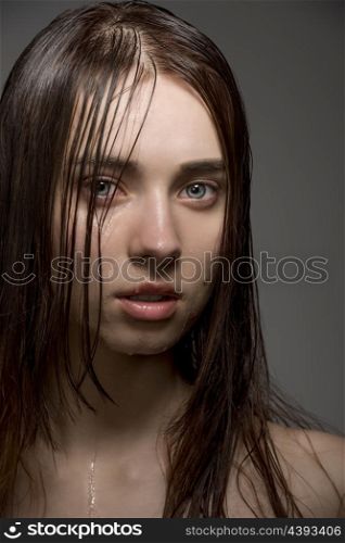 pretty clean brunette female with wet skin and hair, water drops on the visage looking in camera with sensual eyes. Close-up portrait
