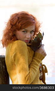 pretty close up of red-haired woman playing with leaf outdoor