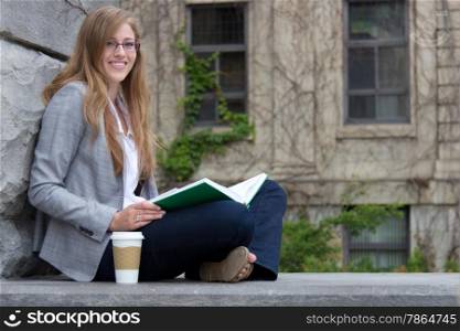 Pretty college student reading a book outdoor