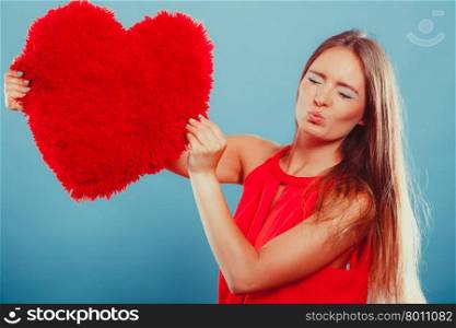 Pretty cute young woman girl with red heart shape pillow in studio on blue blowing kiss. Valentines day love.