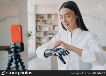 Pretty disabled girl is blogger. European handicapped woman is filming on phone camera. Amputee taking video how to use steel myoelectric arm. Tutorial filming. Rehabilitation technology concept.. Amputee is taking video how to use steel myoelectric arm. Pretty disabled girl is blogger.