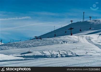 Pretty empty ski piste with chairlifts in the background - shot in Livigno, Italian Alps