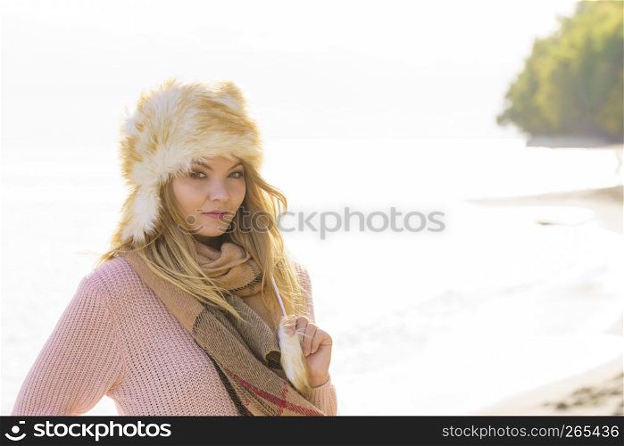 Pretty fashion model wearing furry warm hat enjoying sun during spring or autumn weather.. Fashion model enjoying sun