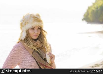 Pretty fashion model wearing furry warm hat enjoying sun during spring or autumn weather.. Fashion model enjoying sun