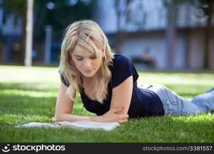 Pretty female reading book while lying on grass