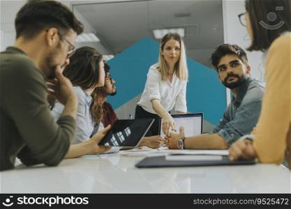 Pretty female team leader talking with mixed race group of people in the small startup office
