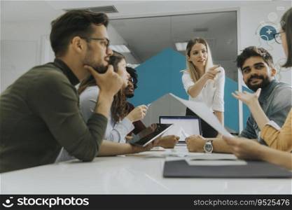 Pretty female team leader talking with mixed race group of people in the small startup office