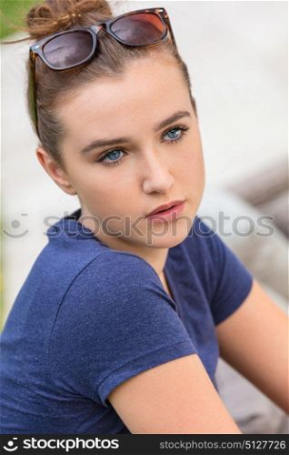 Pretty female teenager girl or young woman with blue eyes outside wearing sunglasses