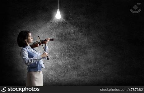 Pretty female violinist. Young woman playing violin and glowing light bulb hanging above