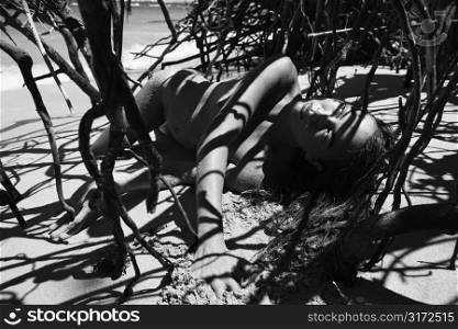 Pretty Filipino nude young woman on beach in tree shadows in Maui, Hawaii.