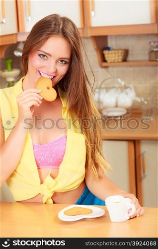 Pretty girl biting heart shape gingerbread cookie. Gorgeous woman relaxing while eating delicious biscuit food.