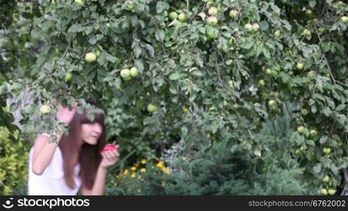 Pretty girl eating red apple in the garden