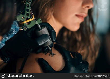 Pretty girl getting a shoulder tattoo. Toned image