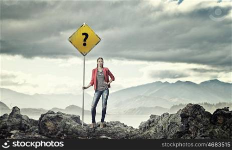 Pretty girl hitchhiker. Young girl in red jacket on mountain showing roadsign