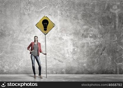 Pretty girl in concrete room. Young girl in red jacket in room showing roadsign