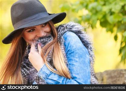 Pretty girl in park. Fashion and style of female. Attractive and fashionable woman outdoor. Portrait of charming young lady hiding in fur waistcoat in park.