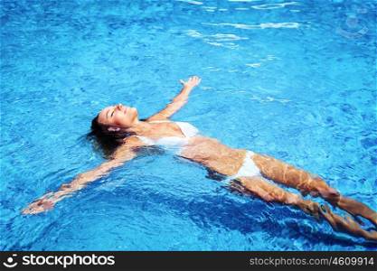 Pretty girl in swimming pool, relaxing in cold refreshing water on hot summer day, enjoying life, spending holidays on the beach resort
