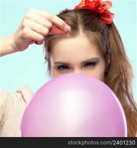 Pretty girl is going to pop a balloon with a pin