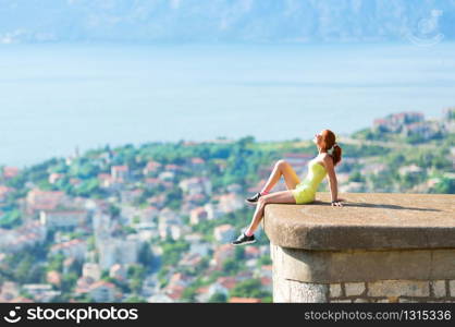 Pretty girl is sitting over the city