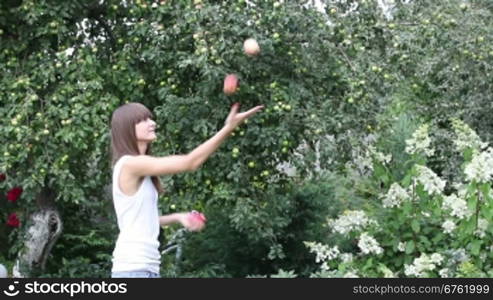 Pretty girl juggling with three apples