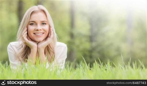 Pretty girl laying on grass. Blonde pretty girl laying on the grass in spring park and smiling