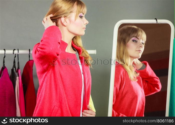Pretty girl looking into mirror.. Pretty happy woman in mirror with clothing from new collection wardrobe. Young undecided shopper girl choosing in second hand. Shopping sale concept.