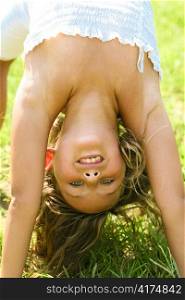 Pretty girl making gymnastic moves on grass looking into camera
