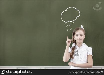 Pretty girl of school age standing at blackboard. Back to school