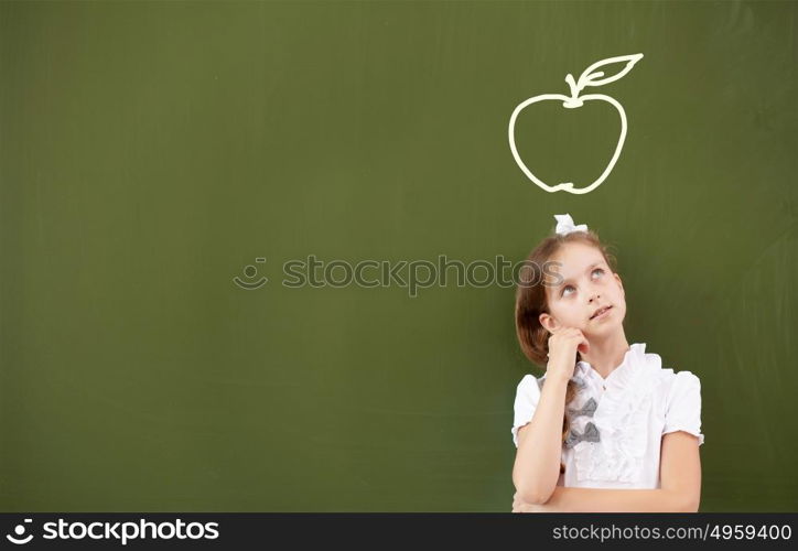 Pretty girl of school age standing at blackboard. Back to school