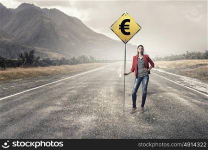 Pretty girl on asphalt road. Young girl in red jacket on road showing roadsign