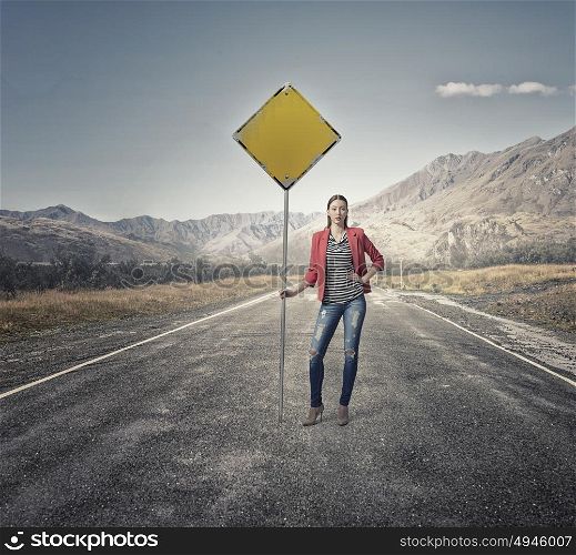 Pretty girl on asphalt road. Young girl in red jacket on road showing roadsign