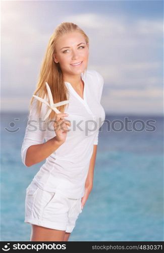 Pretty girl on the beach in sunny day with starfish in hand, wearing cute white beach clothes, having fun on tropical resort on Maldives