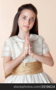 Pretty girl on the day of their communion in prayer with the rosary in his hands