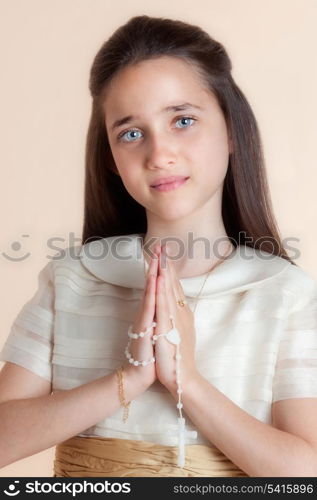 Pretty girl on the day of their communion in prayer with the rosary in his hands