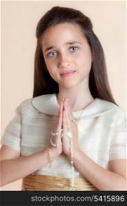 Pretty girl on the day of their communion in prayer with the rosary in his hands